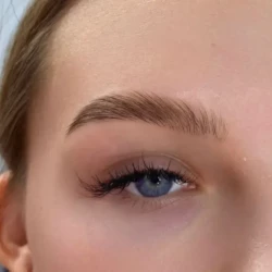 a closeup of a woman's face with blue eyes showing her eyebrows done well as part of a beauty treatment by waxination.nl in Amsterdam